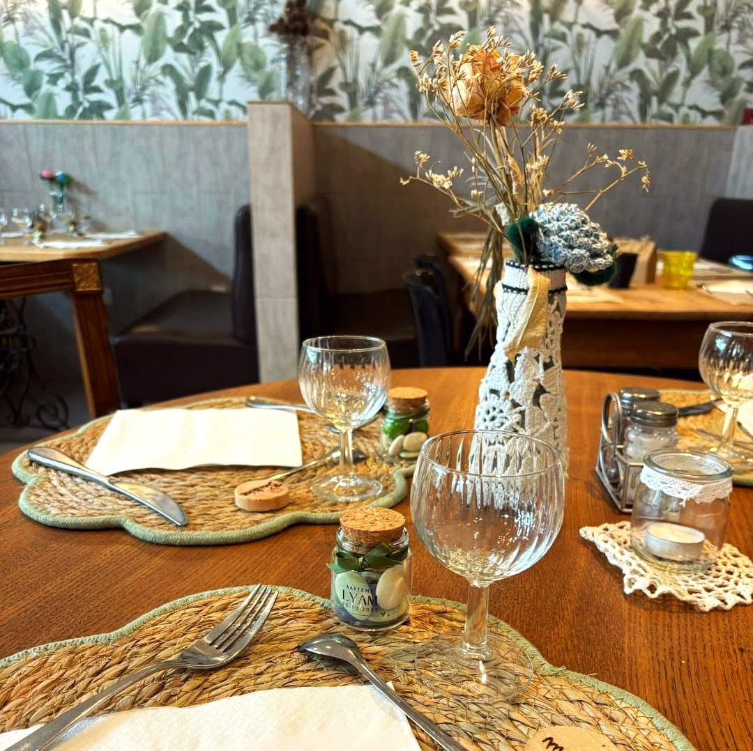 Table dressée : sets de table en paille tressée, verres, bouquet de fleurs séchées et prénom gravé sur un rond de bois